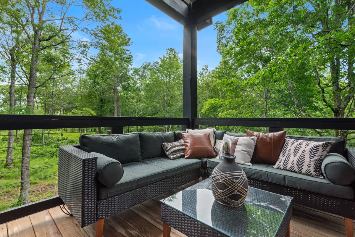 The image captures a cozy outdoor seating area with comfortable chairs and a decorative vase, set against a lush, green backdrop. The space is designed for relaxing and socializing, with the natural environment inviting guests to watch wildlife or stargaze at night. The tranquil mood is perfect for unwinding after a day of exploring local attractions.