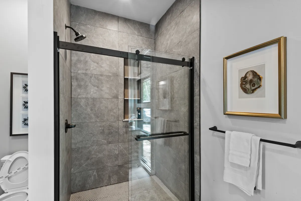 A modern bathroom with a glass shower enclosure, framed artwork, and fresh towels on the rack. The fixtures are stylish and contemporary, evoking a spa-like atmosphere ideal for relaxation and self-care.